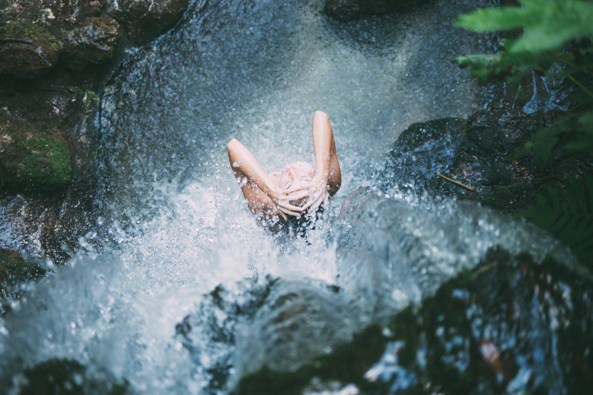 Person diving into a natural pool surrounded by greenery