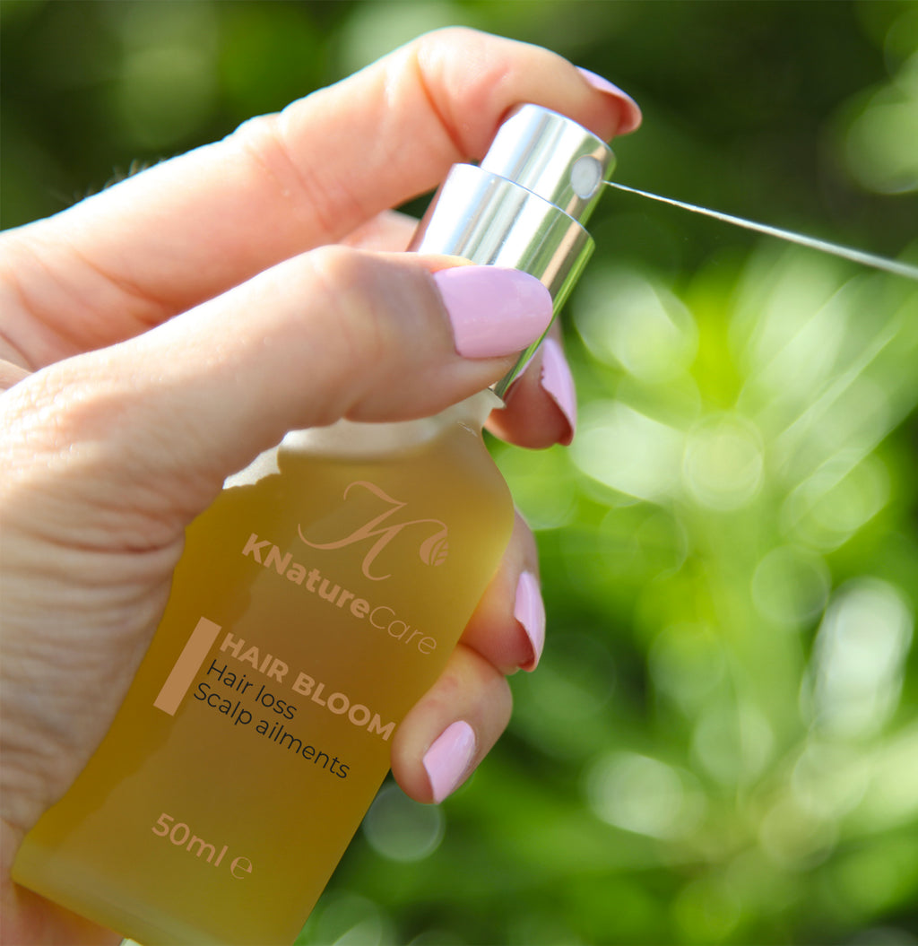 Hand spraying Hair Bloom Scalp Oil outdoors