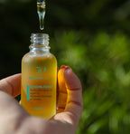 Hand holding the Moonlight Night Facial Oil bottle with dropper, outdoors
